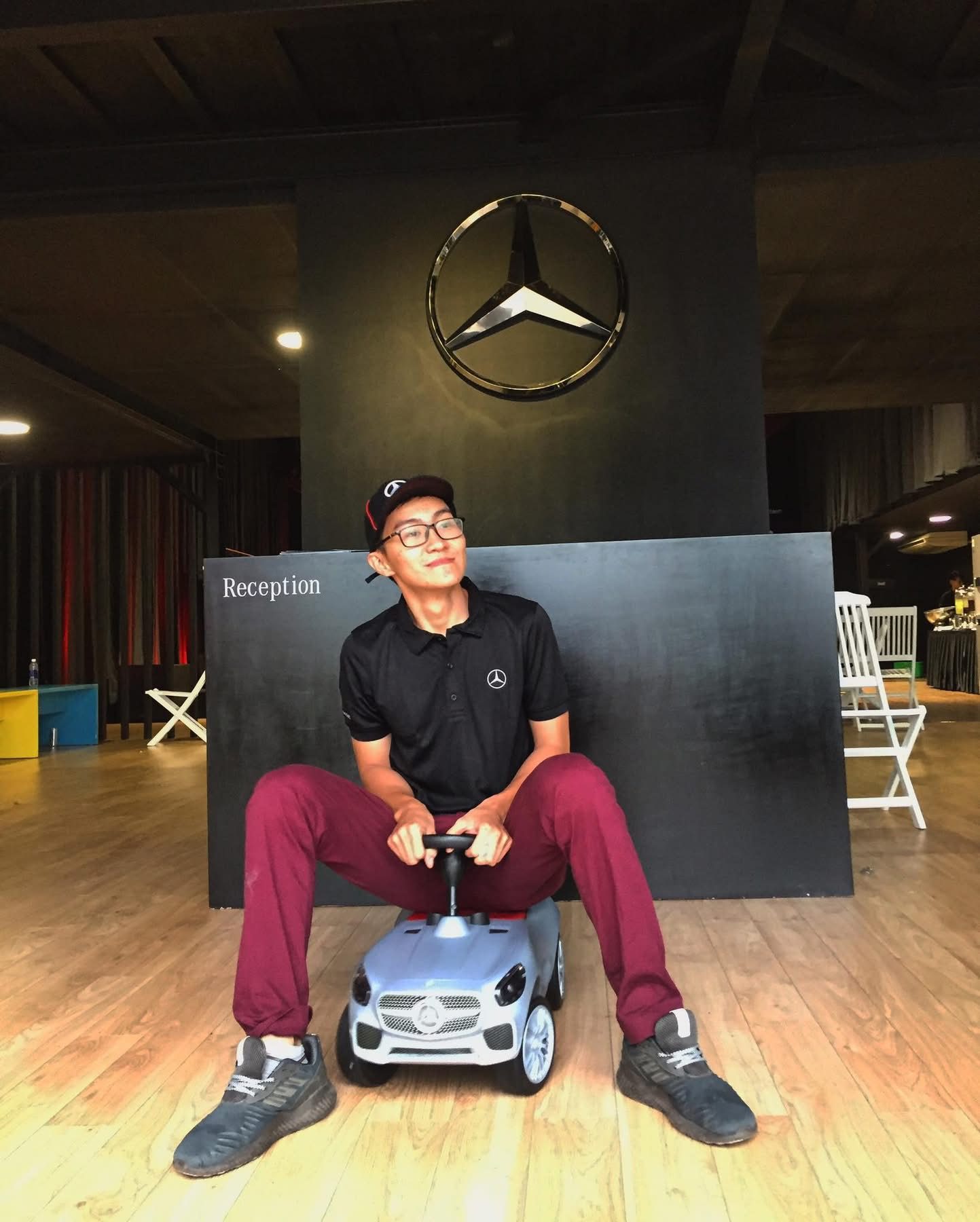 Luke Duong goofing around on a kid's ride-on car at a Mercedes-Benz event