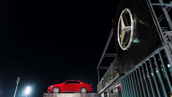 Mercedes-Benz sedan photographed at night by the dealership sign